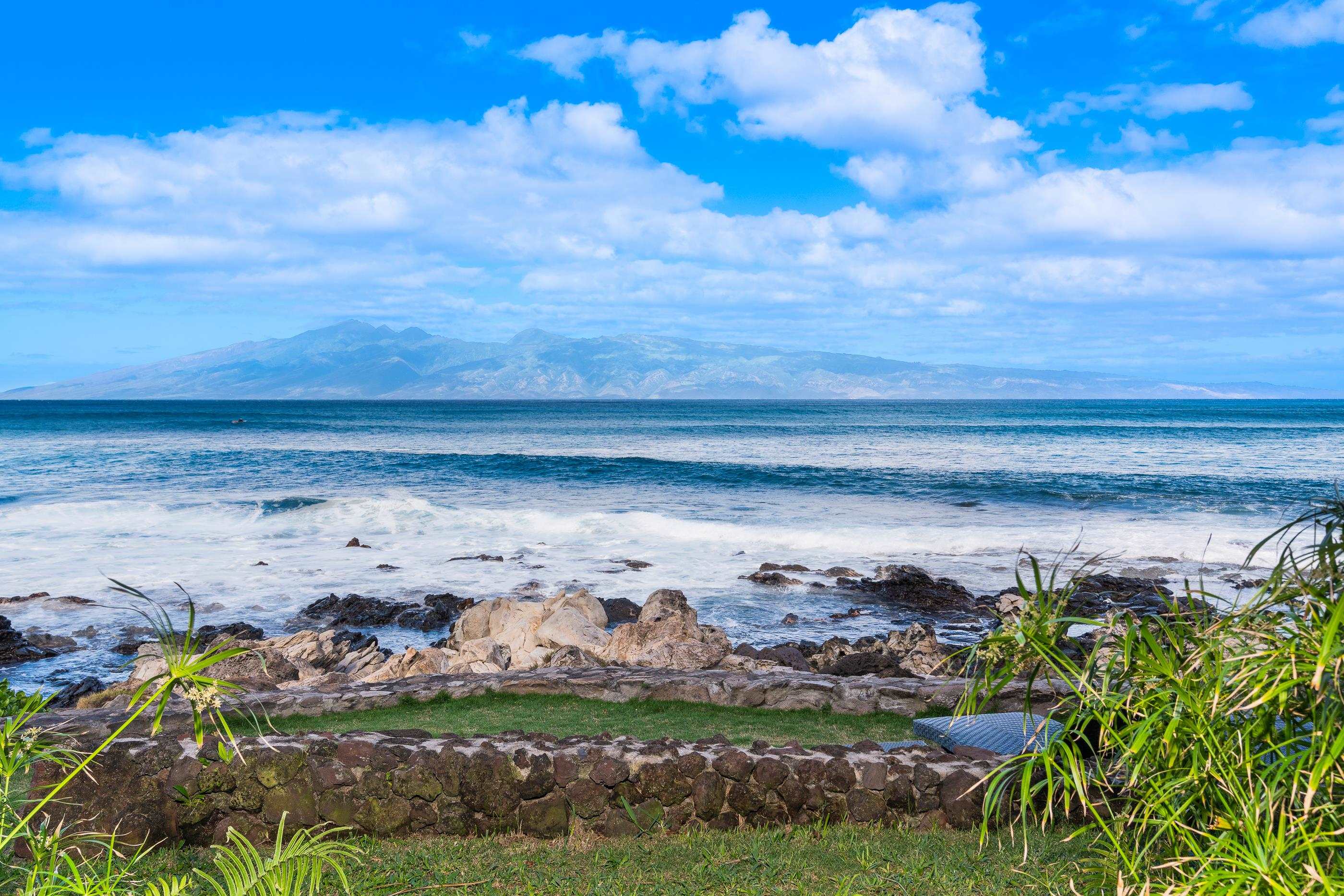 Swell breaking over the rocks at the foot of the lawn, the island faint beyond