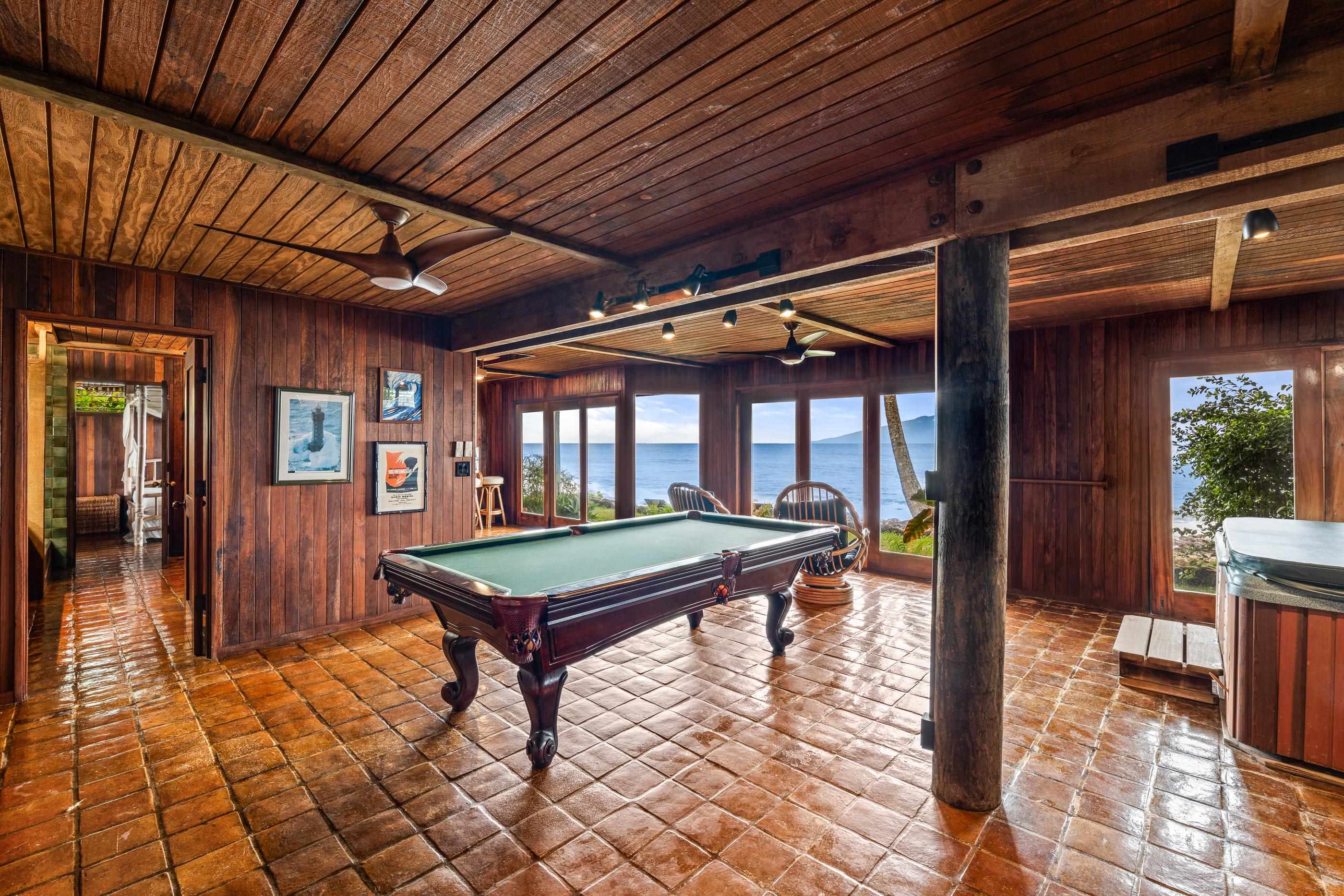 The game room's full-size pool table on terracotta tile, ocean light through the windows